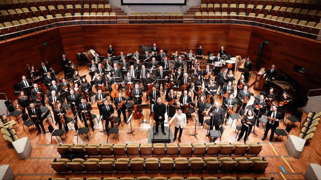 Músicos de la Orquesta Filarmónica de Bogotá de pie en escenario cultural