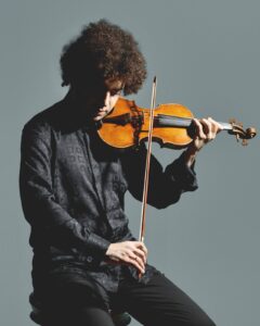 Violinista interpretando instrumento en foto de cuerpo entero